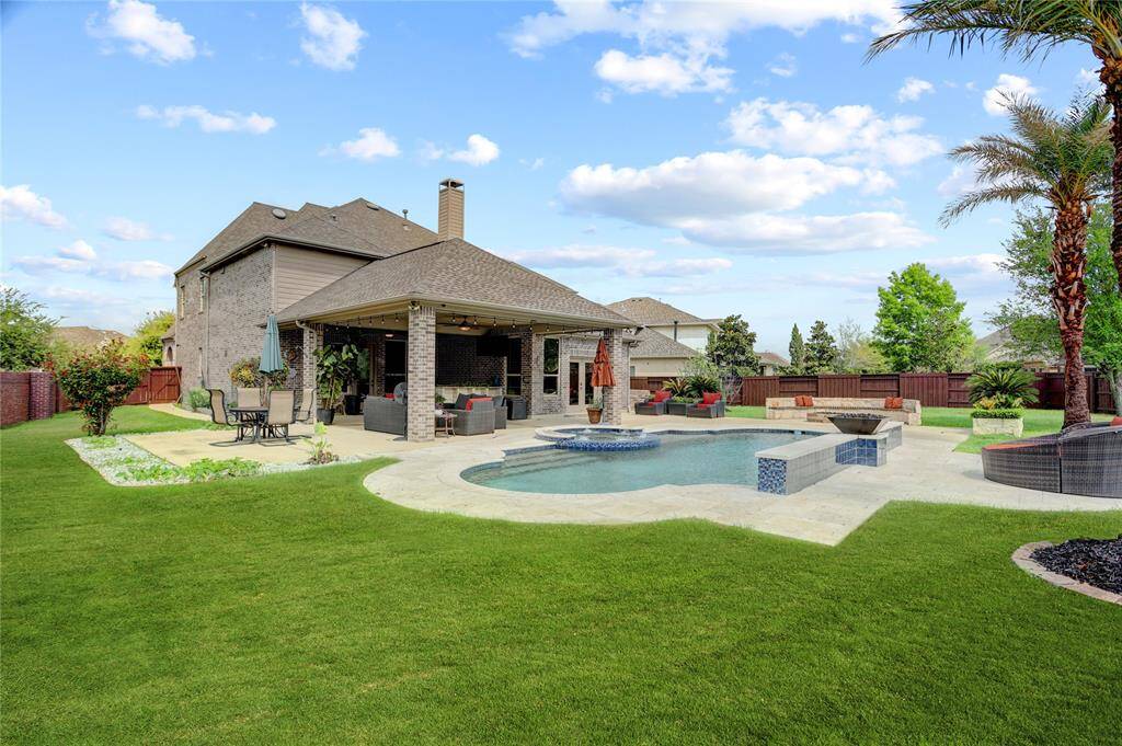 A sleek backyard features a modern pool with spa, generous patio seating, and vibrant landscaping—ideal for weekend fun or quiet afternoons.
