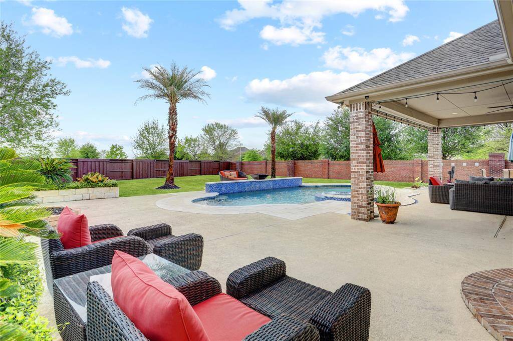 Surrounded by trees and a manicured lawn, this backyard includes a stylish pool, shaded seating, and patio space for both entertaining and relaxation.