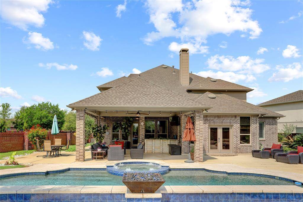 The expansive backyard of this brick home features a covered patio, lush landscaping, and a sparkling pool—an ideal setup for both entertaining and everyday enjoyment.