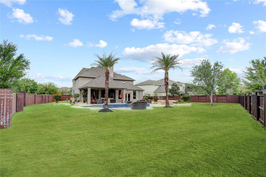 Enjoy summer days in this backyard with a large pool, green lawn, and ample patio space. Fenced for privacy and designed for leisure.
