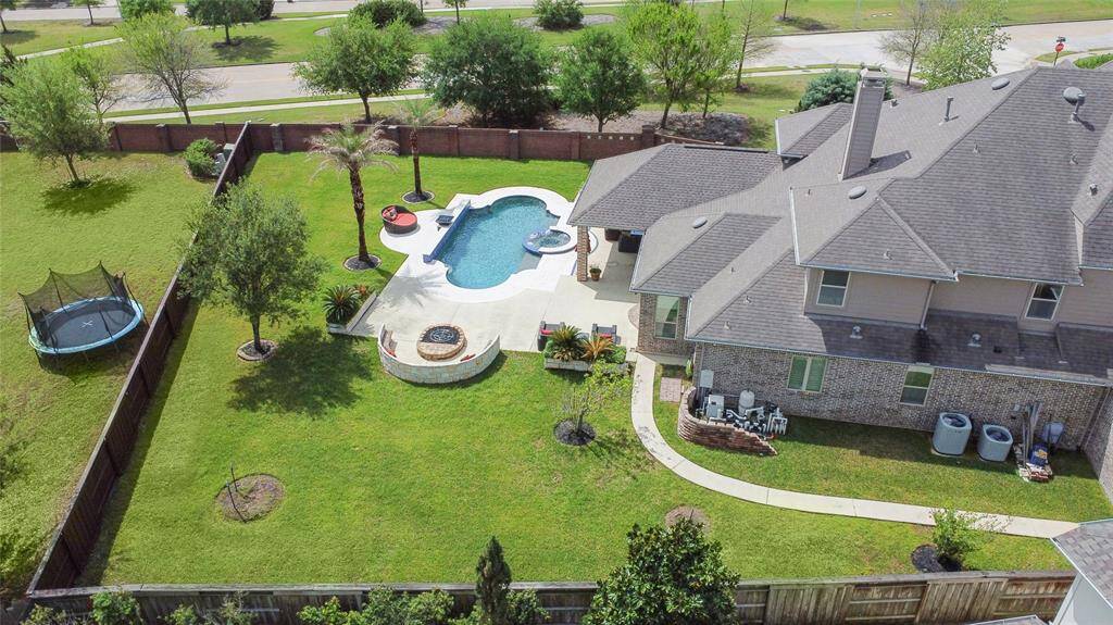 The backyard includes a pool, spa, patio, and landscaped greenery, along with space for outdoor activities. A nearby play area adds flexibility.