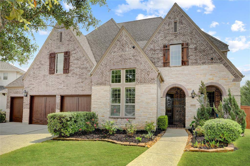 With timeless curb appeal, this two-story brick and stone home features a pitched roofline, wooden shutters, and a stately arched entrance. A three-car garage and tidy front landscaping complete the inviting exterior.