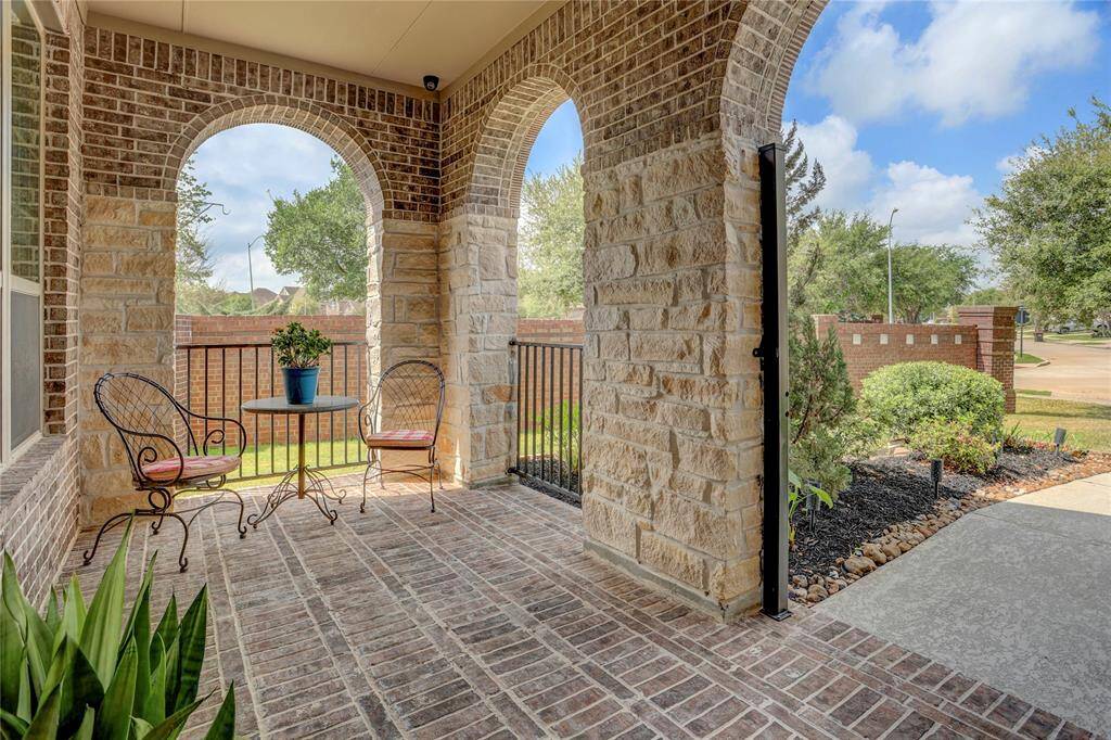 Relax under the covered patio adorned with brick arches and lush greenery. This cozy outdoor space is perfect for morning coffee or quiet evenings overlooking the garden.