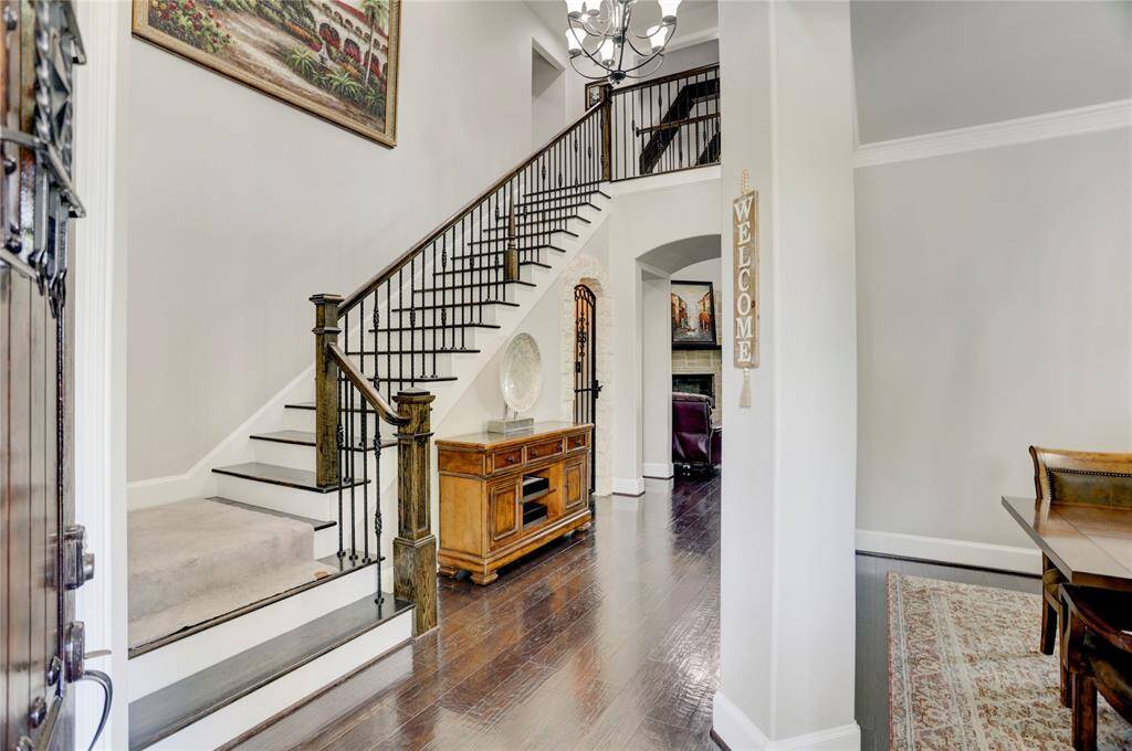 A graceful entryway welcomes you with a carpeted staircase, wrought iron railings, and gleaming hardwood floors. The high ceiling and tasteful décor set the tone for the home’s warm and inviting atmosphere.