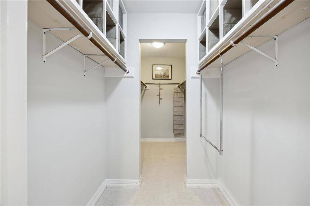 Large primary walk-in closet complete with open shelving and clothing rods.