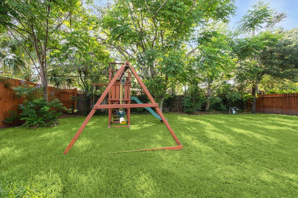 Large backyard complete with outdoor playset and swing set ready for new adventures.