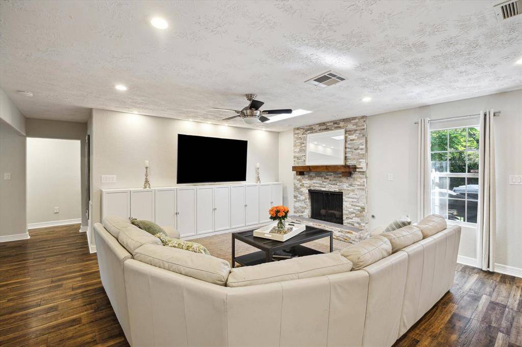 Custom built-ins and a stunning stone fireplace anchor the bright and airy living room.