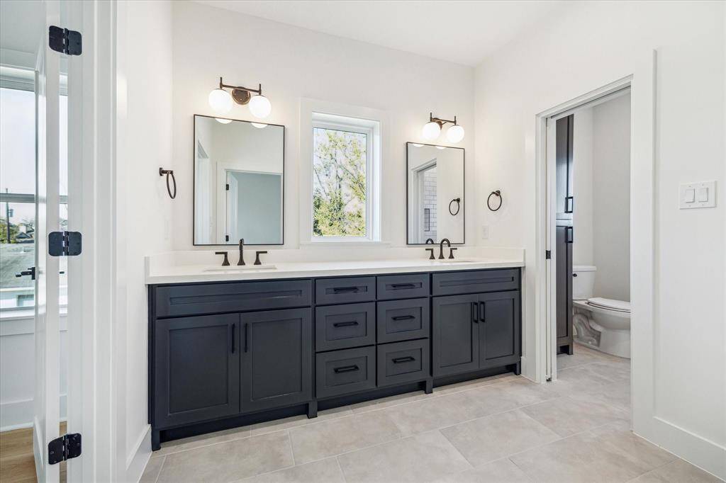 Jack and Jill full bath accessible from both bedrooms with tub/shower combination, classic tiles, dual vanities, decorative fixtures and large casement window inviting natural light