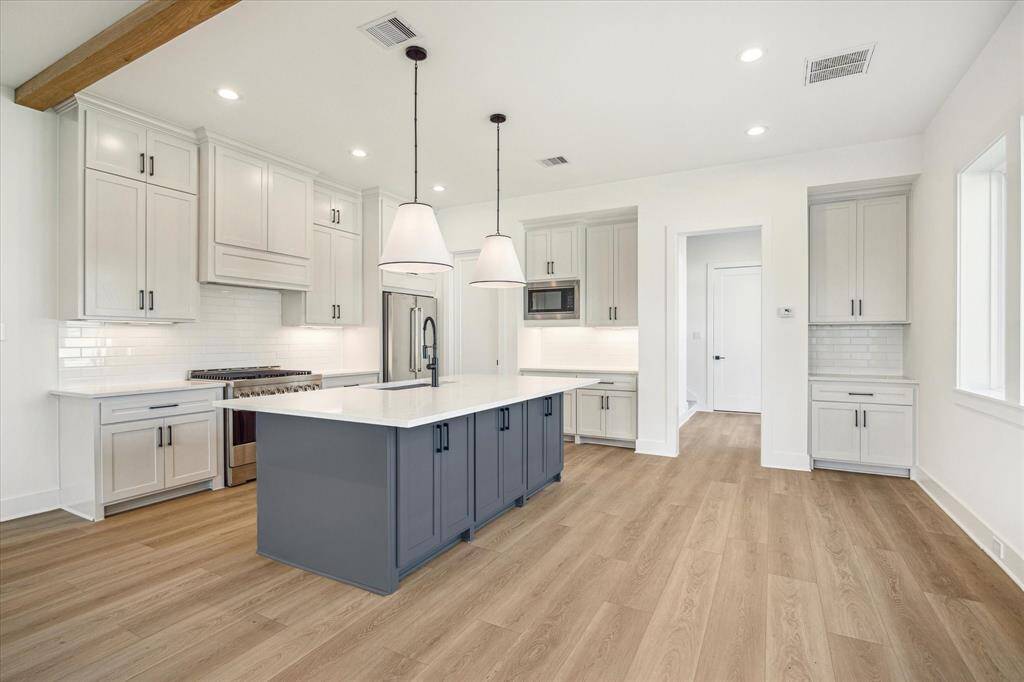 Well-appointed kitchen with modern flair featuring stainless steel appliances and framed vent-a hood. Bar overhang allows for stools to rest under the counter. Space saving closed pocket door pictured center leads to walk-in pantry. This Chefs kitchen features soft close drawers and cabinets allowing to close silently and smoothly