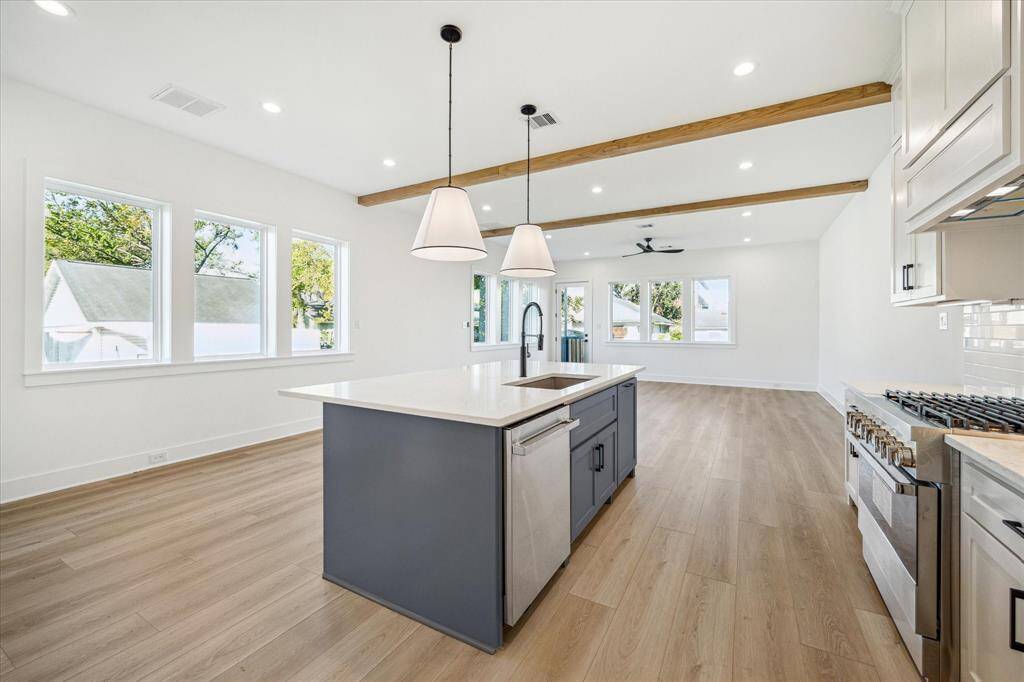 Additional view of the kitchen, wall of casement windows and sleek pendants to illuminate the kitchen island