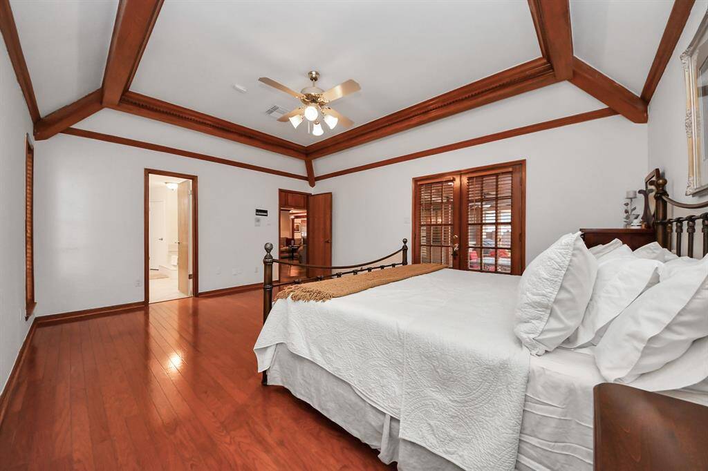 The gorgeous primary suite offers direct access to the screened porch area, and also boasts gleaming hardwood flooring and fabulous ceiling details!
