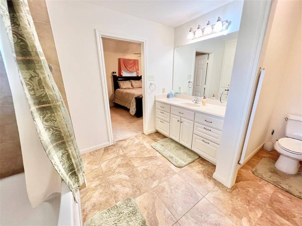 Primary Suite with Poured Marble counters, large garden tub & Shower, tile flooring looking toward the primary bedroom.