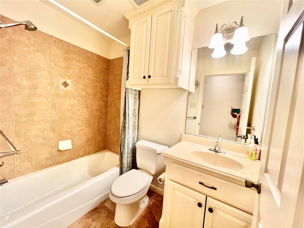 Secondary guest bathroom on this side of home is very nice with custom built cabinets, tiled shower/bath combo.
