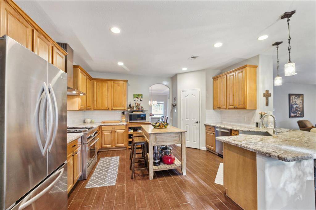 Spacious kitchen with warm wood cabinets, stainless steel appliances, and granite countertops offers a cozy, open layout perfect for entertaining.