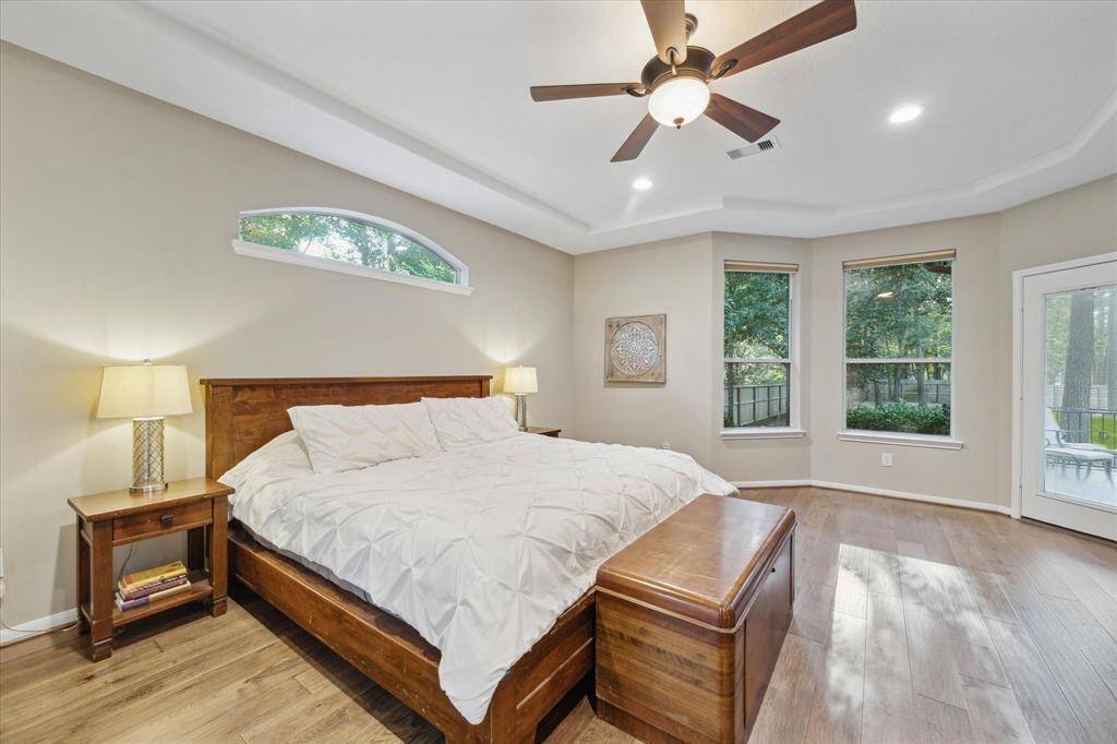 This primary bedroom features a tray ceiling with beautiful backyard views and a private patio entryway.