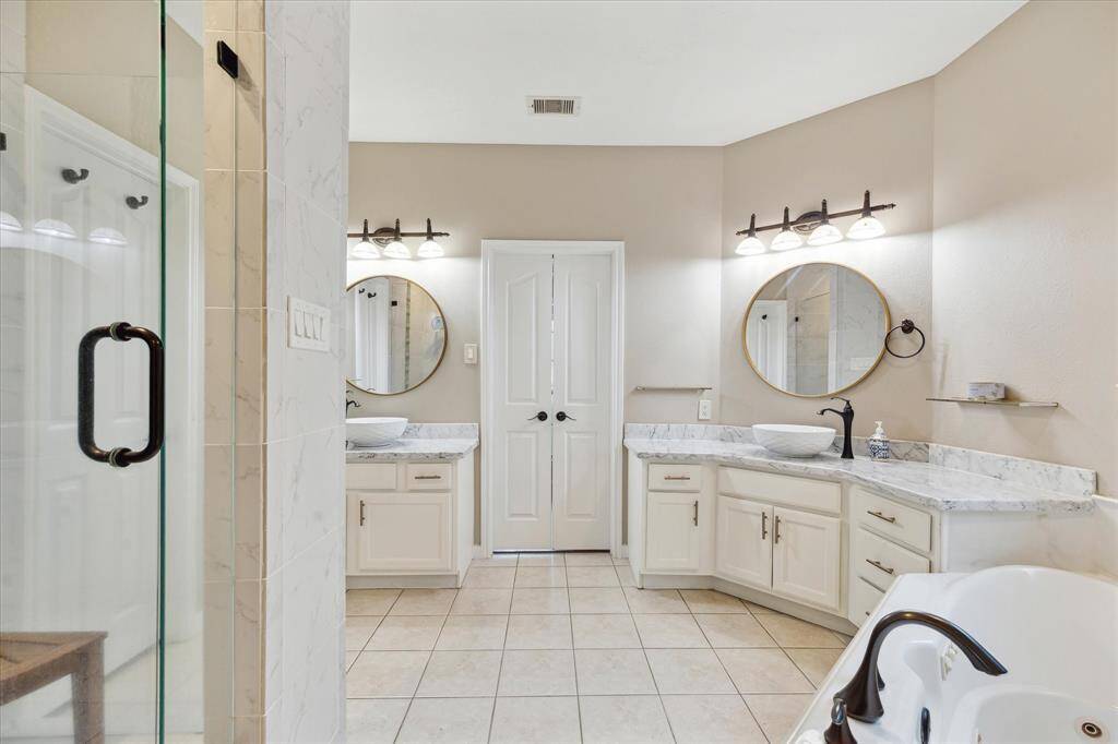 The primary ensuite bathroom features dual vanities, modern fixtures, a spacious walk-in glass shower, and spa tub.