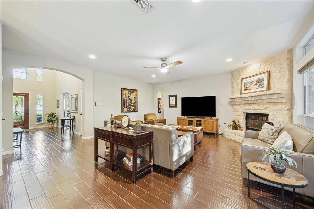 This inviting living room features a cozy stone fireplace, sleek flooring, and elevated design accents.
