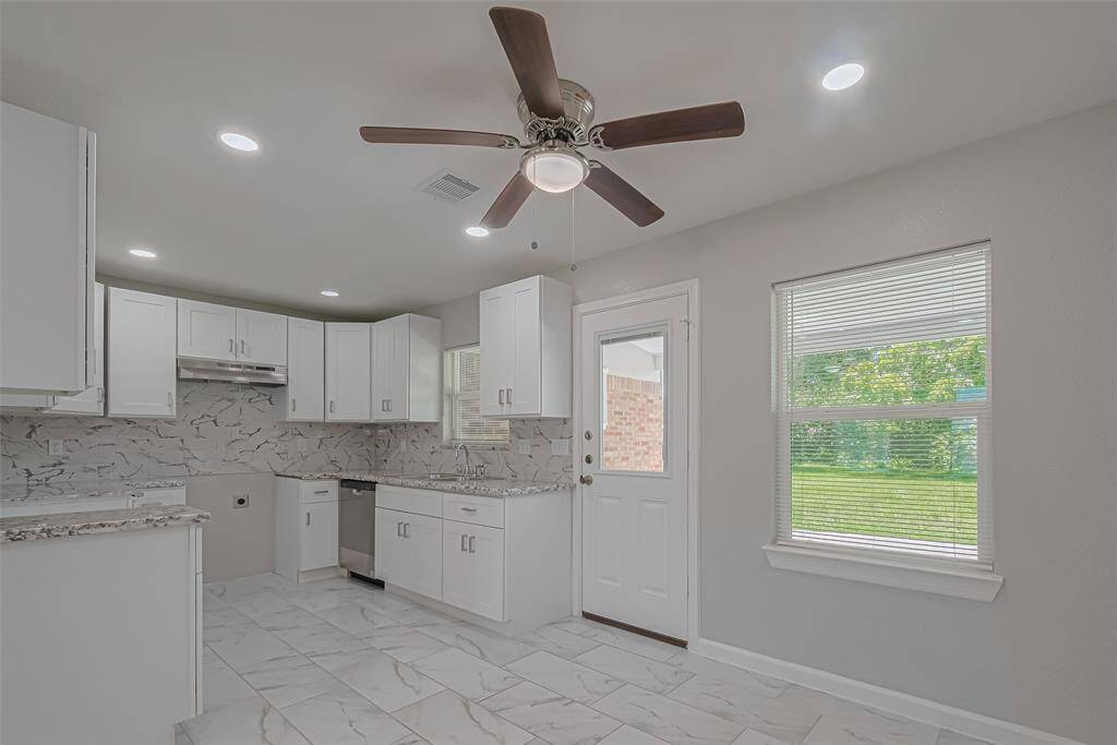 The dining area sits beside a large window overlooking the backyard, offering a charming space to gather with views of greenery.