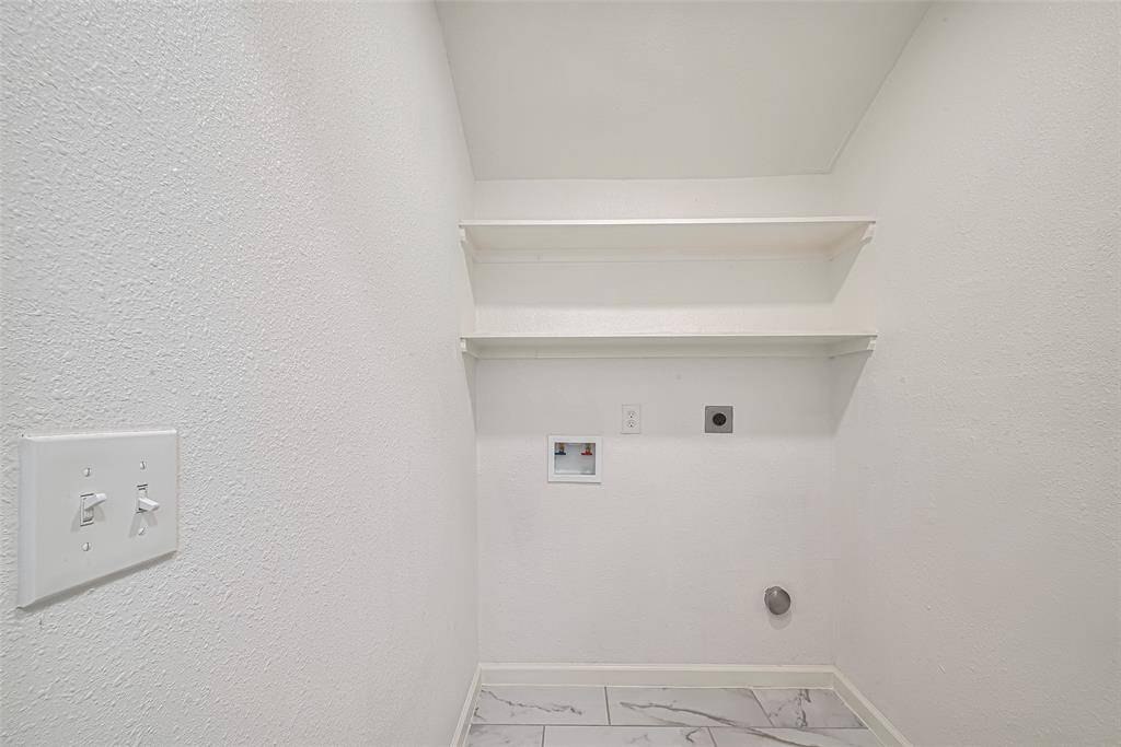 The laundry room provides ample room for side-by-side machines, with built-in shelving above for added utility and storage.