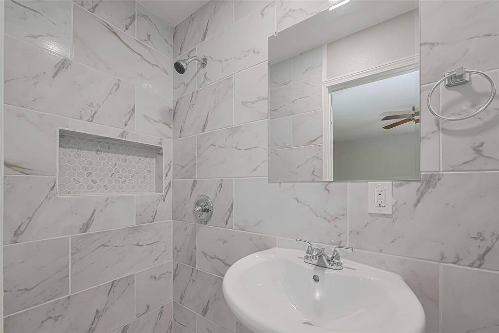 The private en suite features a shower area and gray-and-white tiled finishes that echo the home’s cohesive design.