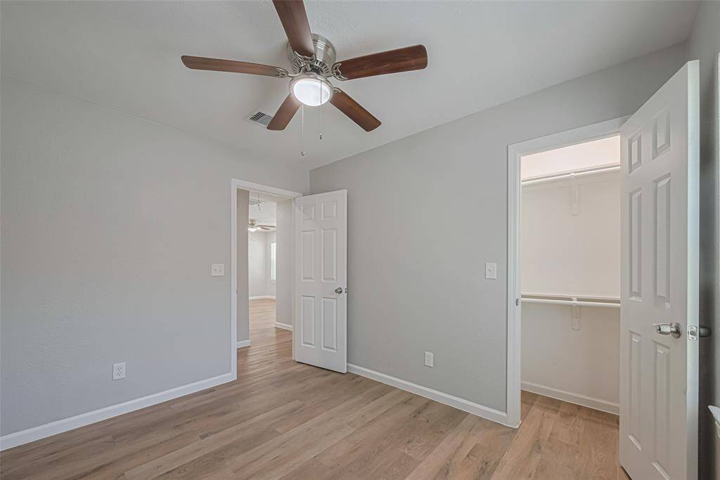 This secondary bedroom includes a full entry closet and ceiling fan, offering comfort and utility for guests or additional household members.