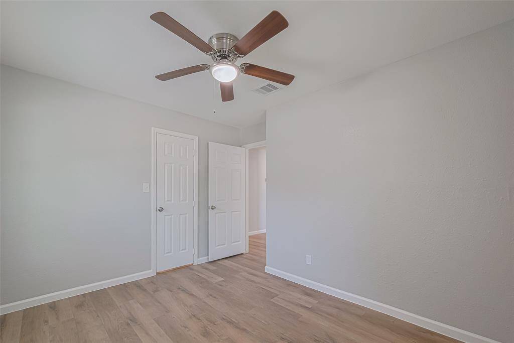 The third bedroom continues the theme of comfort with neutral tones, a ceiling fan, and wood-style flooring.