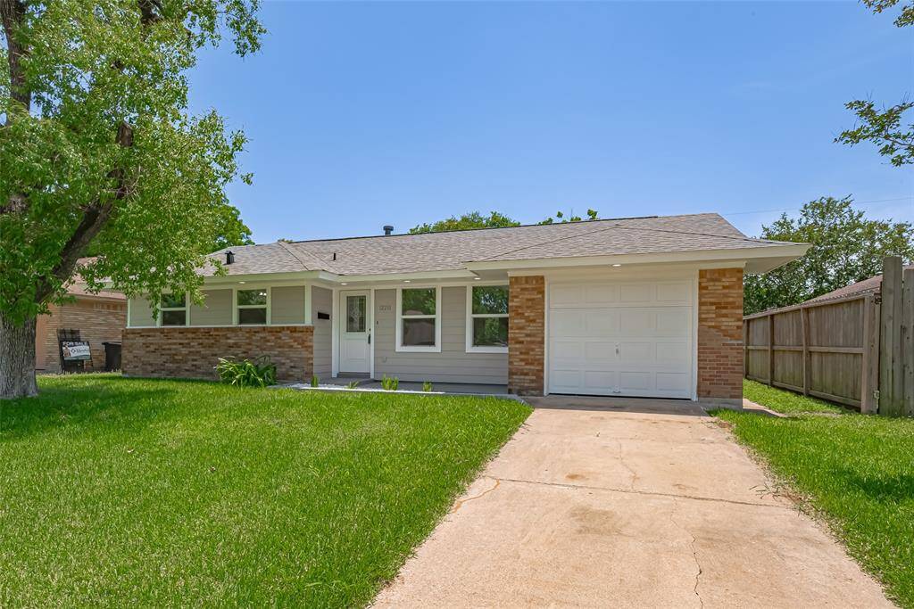 A clear look at the front of the home, showcasing the green lawn, wide driveway, and clean exterior.