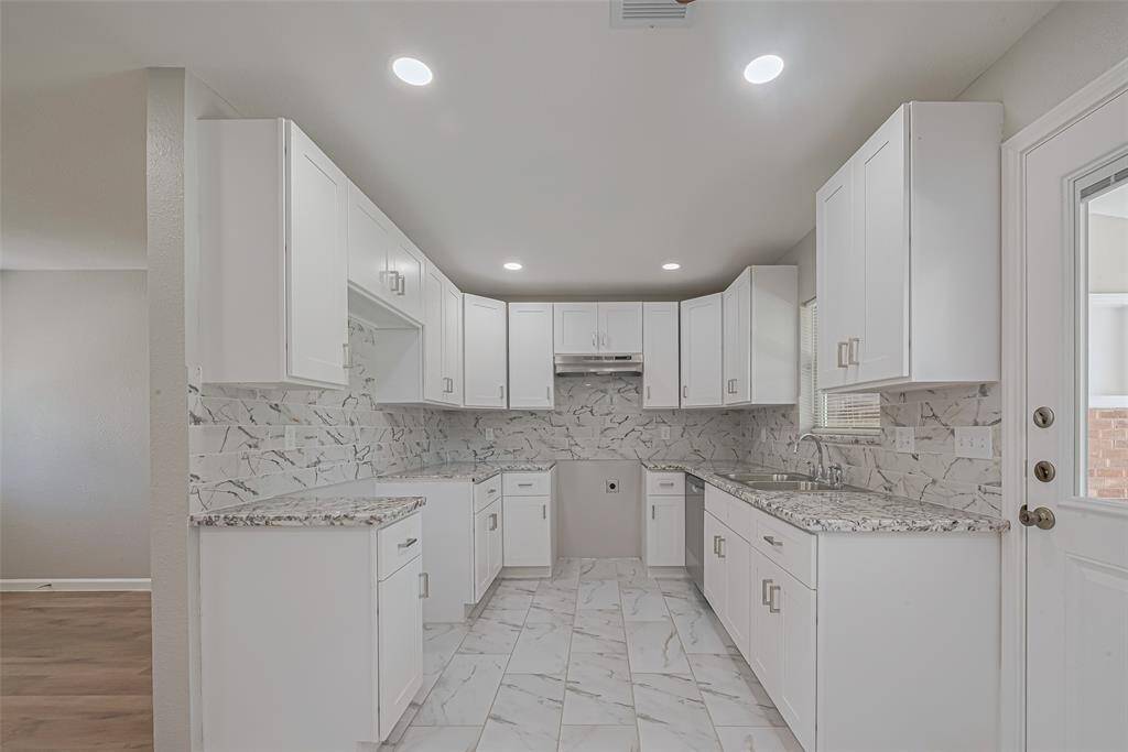 The kitchen includes parallel countertops and an array of overhead cabinets, maximizing space and efficiency.