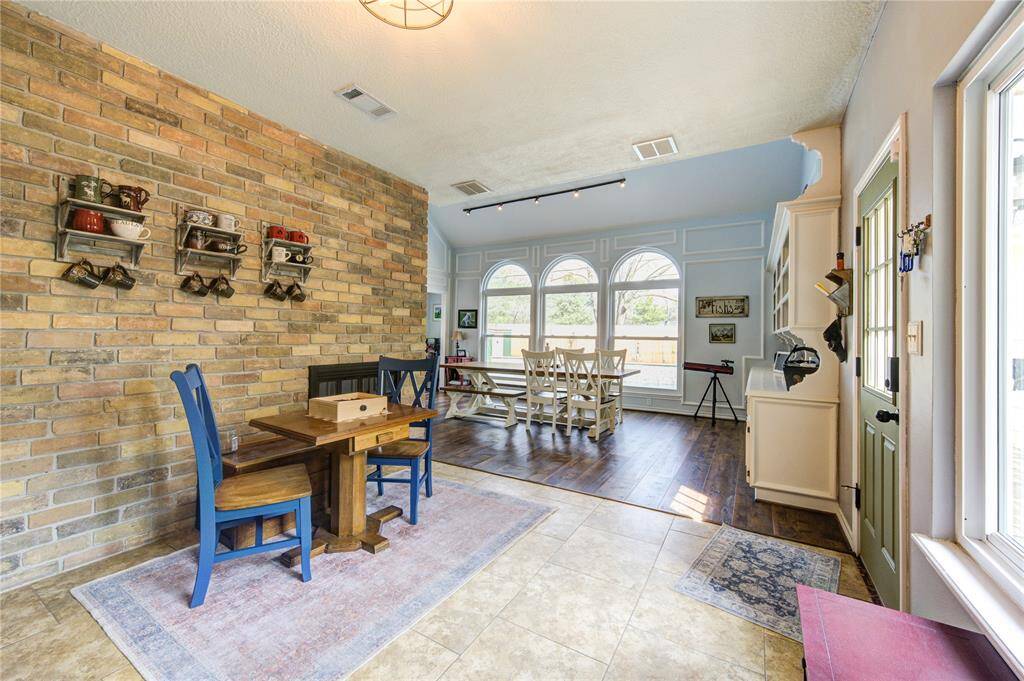 This spacious Breakfast Room features a charming blend of tile and wood flooring, with a rustic brick accent wall, located just off the kitchen.