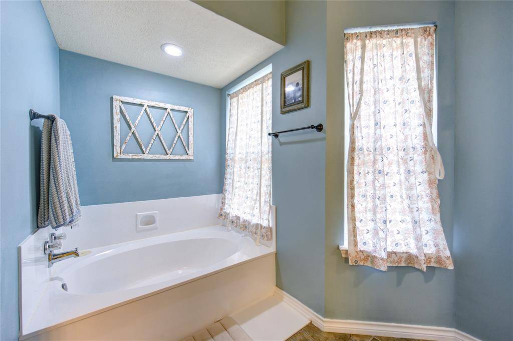 This bathroom features a cozy, light blue color scheme with a spacious white bathtub.