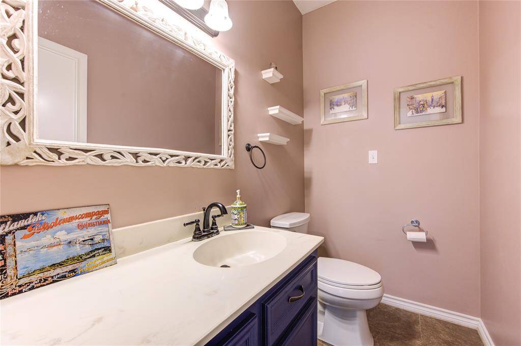 This Half Bath features a modern design with a large decorative mirror, an extended counter and rich dark cabinetry.