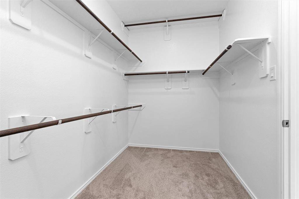 The large Primary walk-in closet features built-in shelving and racks for storage.