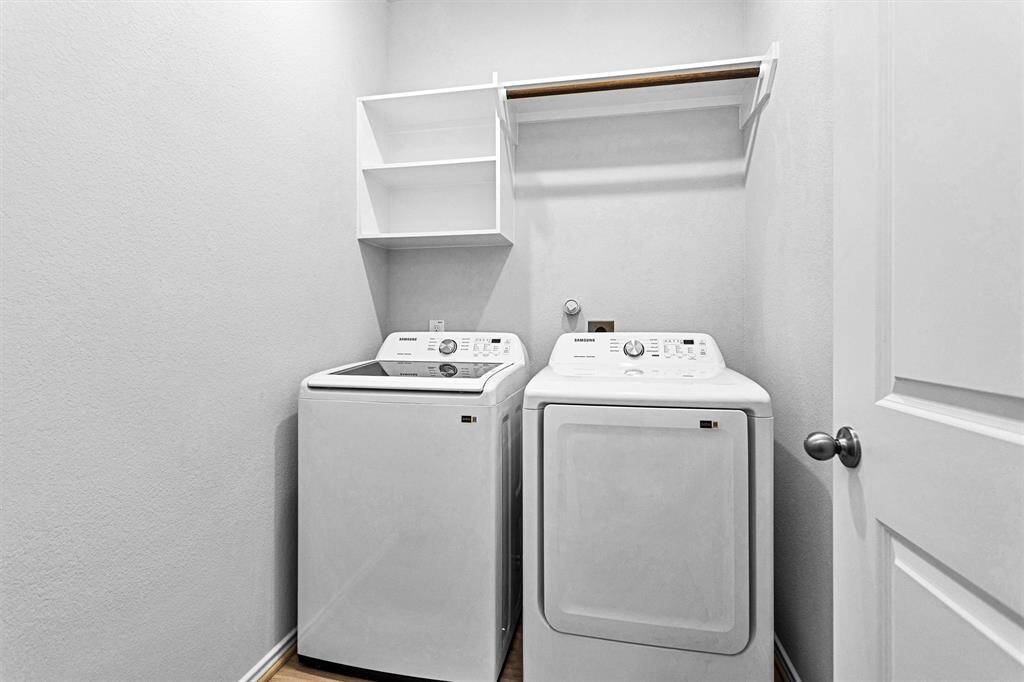Utility room boasts built-in shelving and a hanging rack for storage.