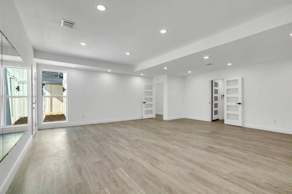 Spacious, modern gym with elegant flooring and plenty of natural light, perfect for a home workout sanctuary.