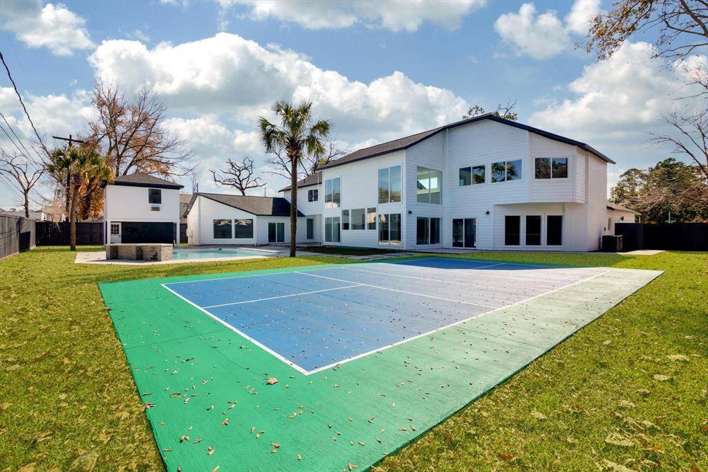 This spacious property features a modern two-story home with large windows, a swimming pool, and a private sports court, all set in a well-maintained backyard. Ideal for outdoor entertainment and family activities.