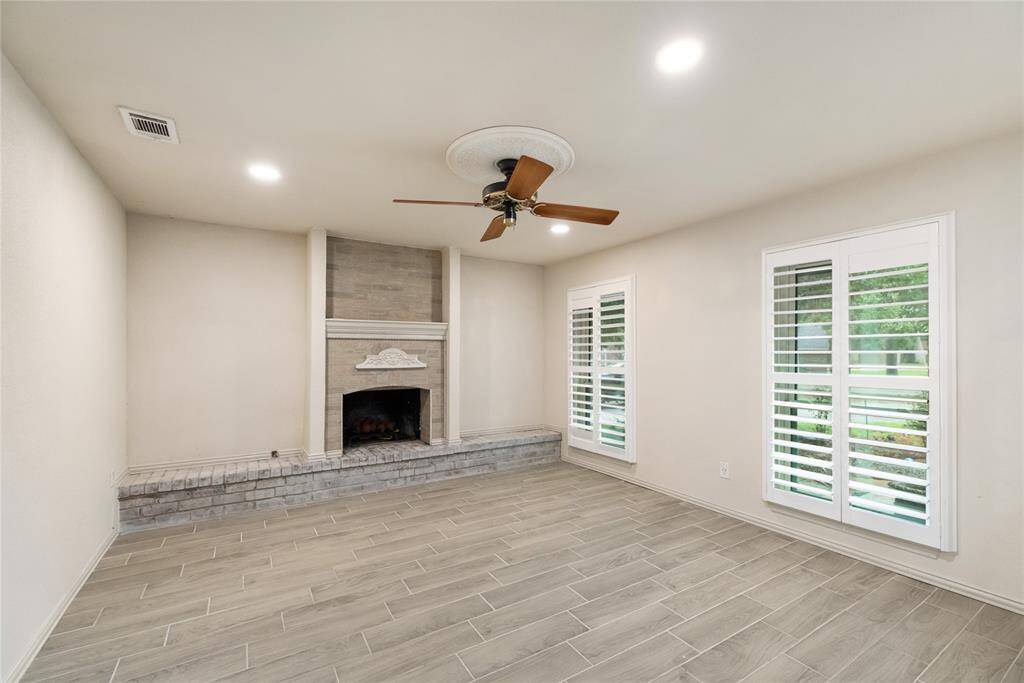 Downstairs, the living room brings cozy comfort with a classic fireplace, wood-look tile floors, and shutter-style windows that let in soft, filtered light. A welcoming space to relax and unwind.