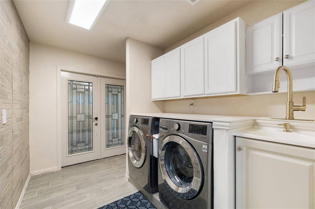 Not your average laundry space—this expansive utility room features a faux brick accent wall, utility sink, and charming French door access. A practical space with unexpected flair.