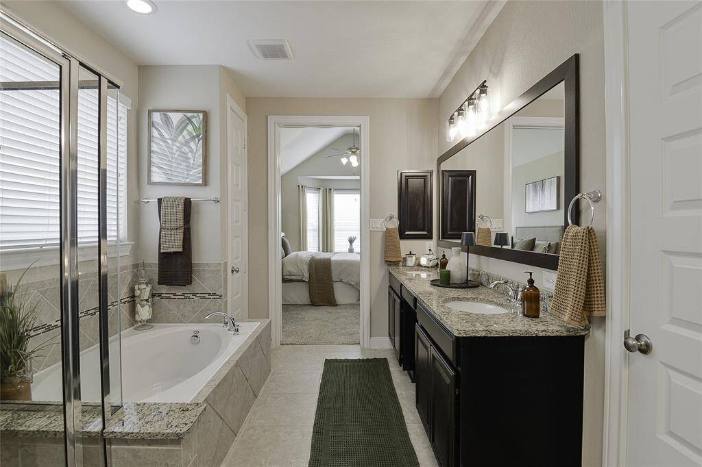 The primary bath is adorned with a spacious double-sink vanity and bathed in natural light, offering the luxury of both a separate walk-in shower and a relaxing soaking tub.