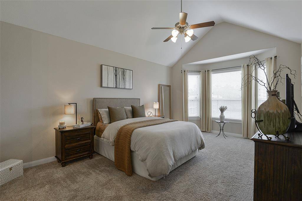 The primary suite boasts vaulted ceilings and large windows that flood the room with natural light, creating a bright, airy, and tranquil retreat.