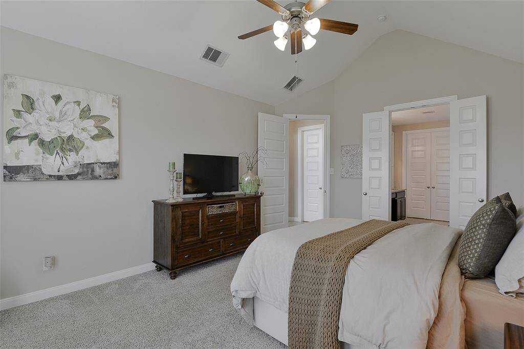 The primary suite boasts vaulted ceilings and large windows that flood the room with natural light, creating a bright, airy, and tranquil retreat.