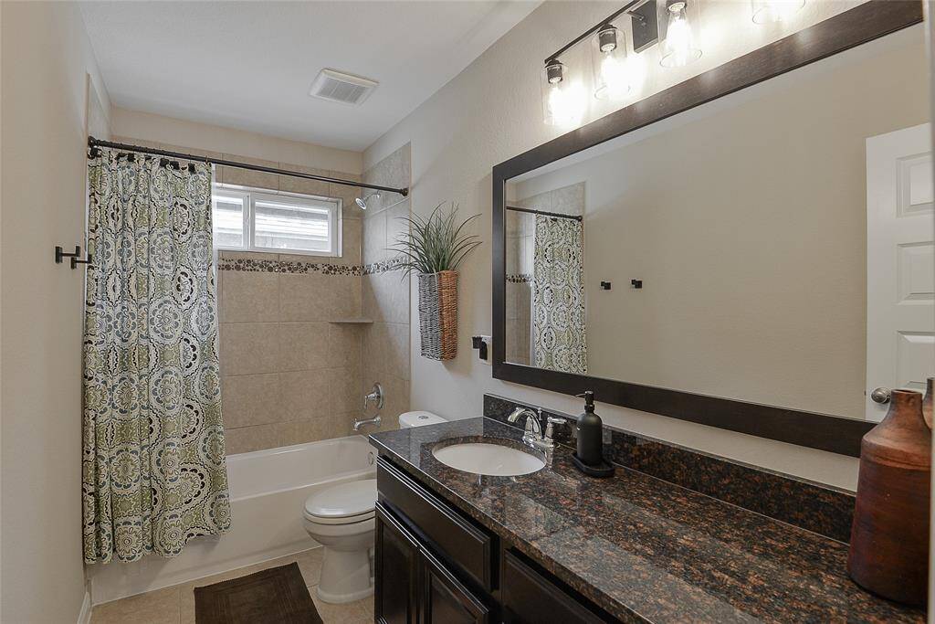 Granite countertops and rich mahogany cabinetry create a cohesive, elegant design that flows seamlessly through all bathroom areas, enhancing both style and function throughout the home.