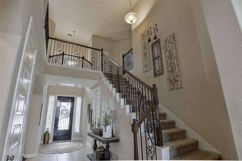 The view from the family room into the upstairs open architecture creates a breathtaking sense of space and connection, showcasing the home's soaring ceilings and elegant design continuity—while offering a clear view of the stately front door and grand entry below.