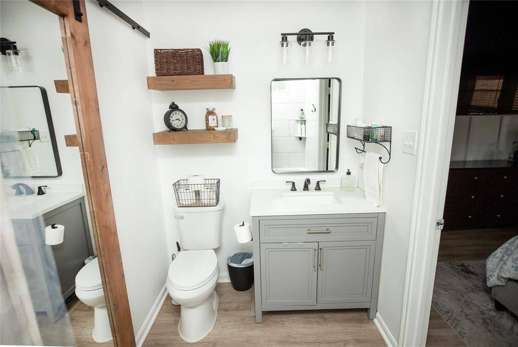 The en-suite bathroom has been fully refreshed and includes new marble countertops, matte black fixtures, floating wood shelves, and a stylish vanity.