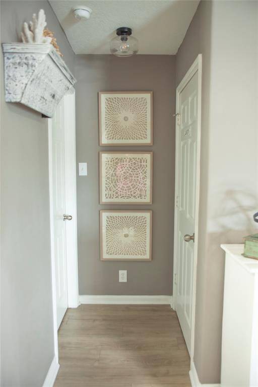 This thoughtfully designed hallway serves as a central connection point between the laundry room and three bedrooms—one of which is currently staged as a stylish office. Neutral-toned walls, wood-look flooring, and updated light fixtures create a cohesive and calming flow.