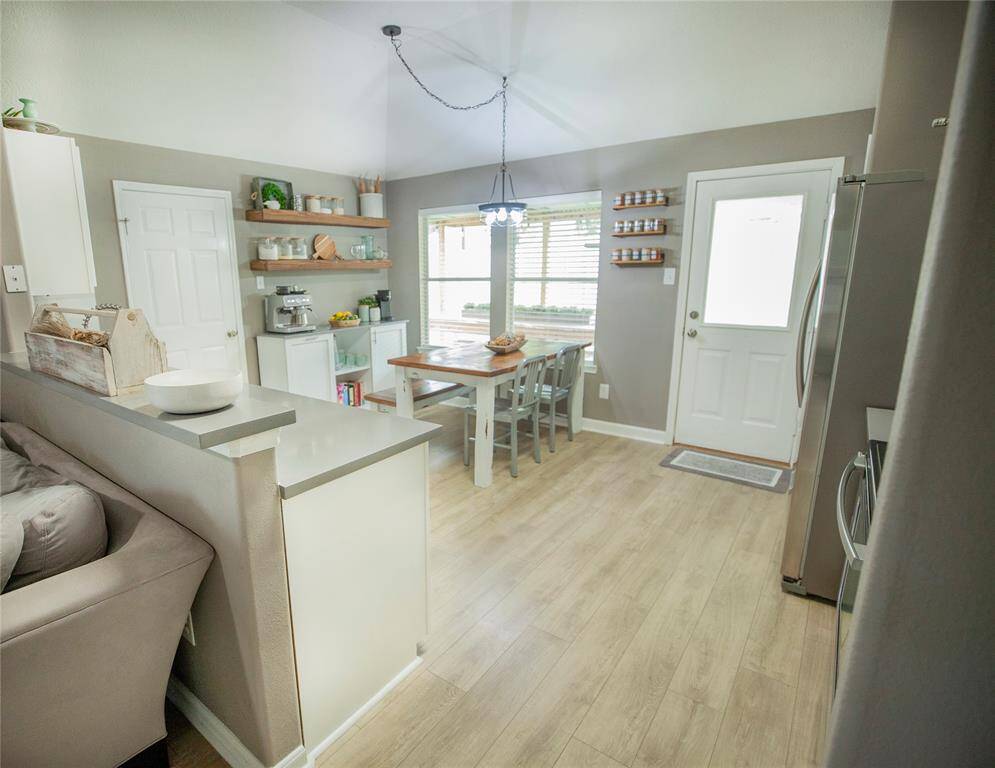 The neutral wall tones and wood-look flooring tie the space together, creating a clean, welcoming atmosphere perfect for everyday living or entertaining. A door leads to the backyard, filling the space with natural light.