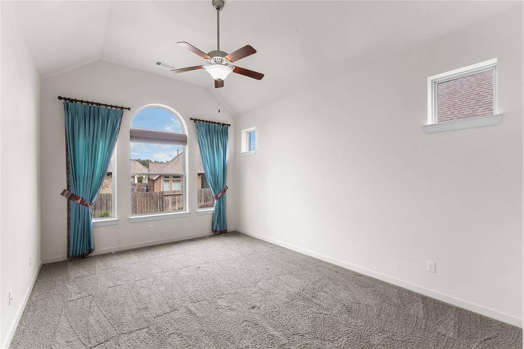 Spacious primary bedroom with three large windows with woven shades.