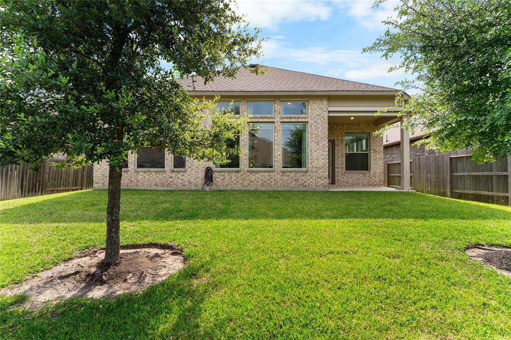 Large backyard with lush grass and mature trees for added privacy.