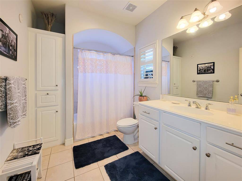 First floor design with white cabinetry and a spacious countertop. It includes a bathtub with  shower, large mirror, and ample storage. The soft lighting and neutral tones create a calming atmosphere.