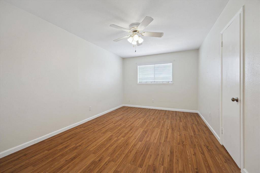 Another spacious bedroom with beautiful floors, neutral walls, and ceiling fan. The window allows for natural light and a large closet.
