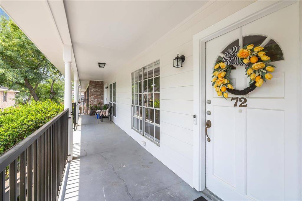 Charming courtyard of a residential complex with two-story buildings. It features a central fountain, well-maintained landscaping, and white fencing. The area is inviting, with stairs leading to upper units and decorative street lamps enhancing the aesthetic.